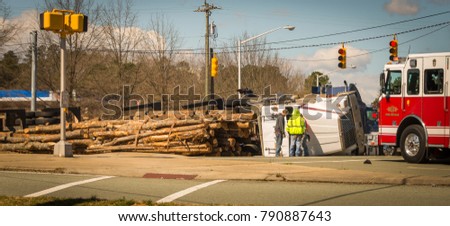Overturned logging truck with work men and fire engine