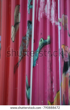 Detail of colorful sheets of steel used as fences. Vertical lines and several bright colors make a textured pattern. The painted metalic surface is corrugated and contains reliefs. 