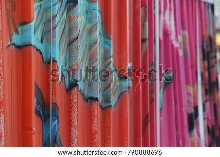 Detail of colorful sheets of steel used as fences. Vertical lines and several bright colors make a textured pattern. The painted metalic surface is corrugated and contains reliefs. 