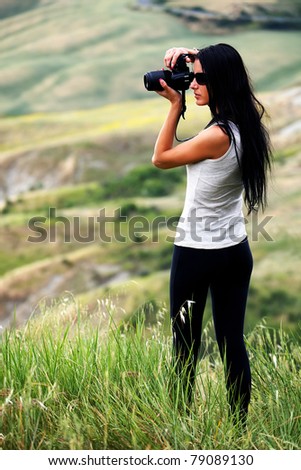 Young brown haired woman photographing in Tuscany
