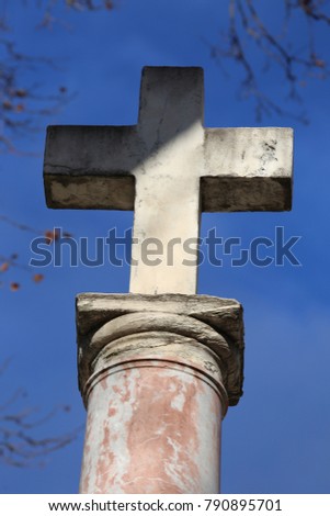 View of a stone cross place on a high column in front of a house. Symbol of the faith in god. A peaceful picture with a blue sky. A tall religious monument in the city of Montpellier France.