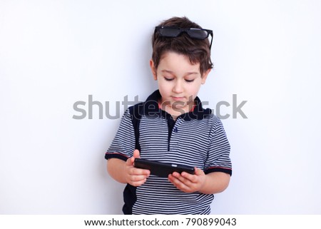 Cute boy with smartphone. Child surfing internet or watching video on mobile phone. Technology, children and parental advisory, lifestyle concept.