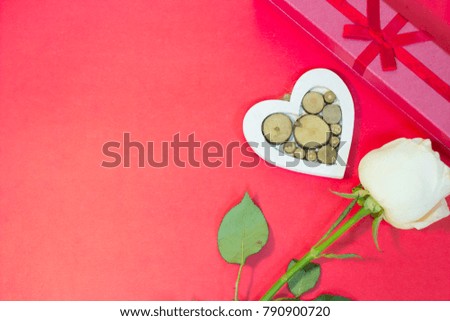 The concept of St.Valentine's Day with a beautiful white rose, a gift box and a wooden heart, top view, copy space