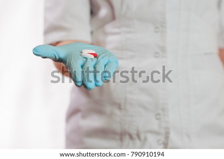 A medical girl holds out a red and white pills
