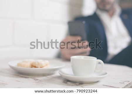 Man taking a picture of morning coffee and cookies on a cafe table