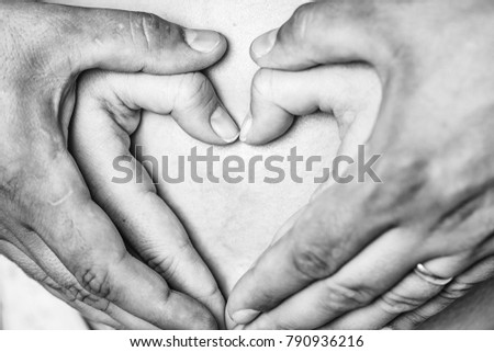 Female and male hands make heart shape cute sign on bare belly of pregnant woman mother parenthood