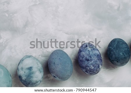 Happy Easter card: Series of ombre eggs with marble stone effect painted with natural dye carcade flower on grey concrete background with blank space for text; top view, flat lay
