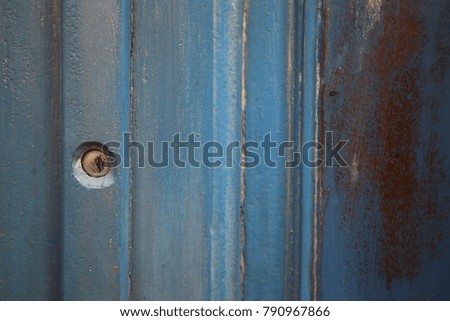 Detail of a blue ancient wooden door. Abstract picture with lines, rectangles, and the keyhole. Patterns and textured surface. Geometrical design and shapes for this isolated element. 