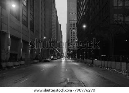 A black and white photo of downtown Chicago. The shot is taken from the middle of the street.
