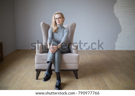 beautiful young caucasian woman  in glasses posing sitting in a chair
