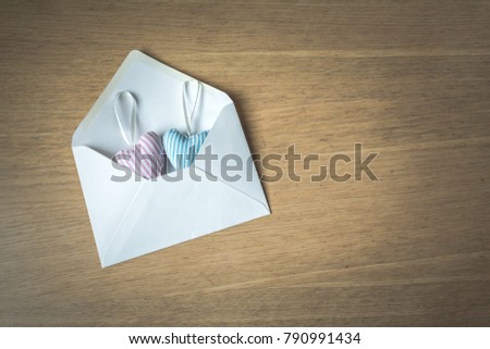 Top view of an envelope with two fabric, textile hearts on a wooden background with copy space, vintage toned. Love or Valentine's day concept