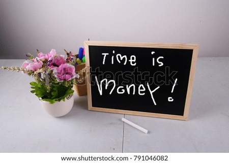 Table decoration with small wooden black board in white background. With time is money on board.
