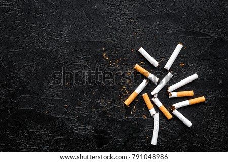 Tobacco. Scattered cigarettes on black background top view copy space