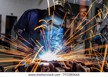 welder is welding metal part in car factory Royalty-Free Stock Photo #791080666