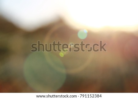 Sun flare light and round bokeh light from the light from top right on the blur background of mountain and flower garden