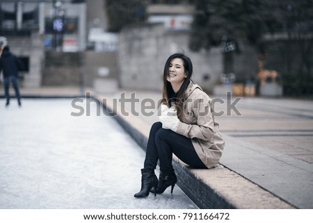 Young woman sitting at skating rink edge in winter