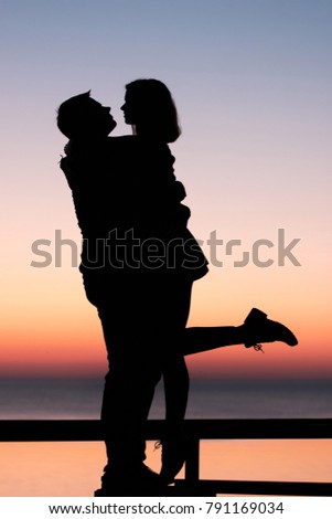 Vintage look image of young couple enyoing time near the ocean during the sunset. Silhouette picture of couple. 