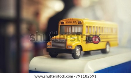 Yellow school bus toy model on bokeh background. Yellow school bus plastic and metal toy model on the natural background and sunrise.