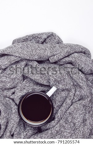 Coffee mug on gray wool scarf on white background with copy space.