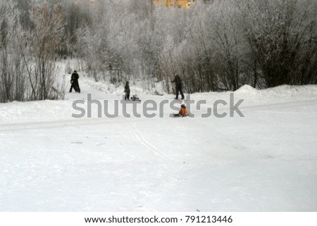 Blurred background. Daytime bokeh. Children ride from a snowy mountain on a sled. Winter background 