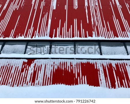 Urban geometry, snow on a red plant wall with windows, background