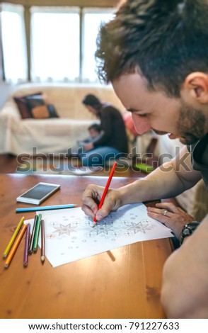 Young man coloring mandalas in the living room