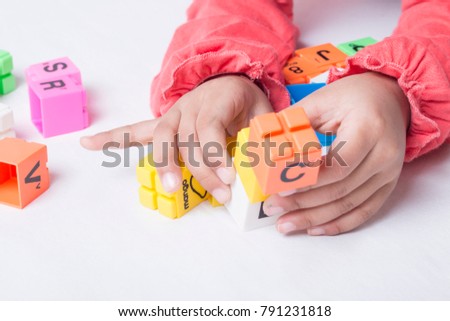 Kid's hands plug and play the alphabets toys. White background.