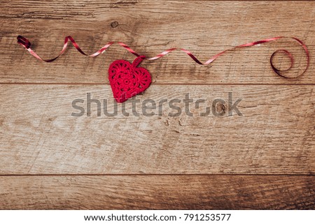 The red ribbon is lined in the shape of a heart on a dark wooden table.Valentines day background. Valentines day table place setting. Backdrop with copy space. Mother's, Women's, Wedding Day concept.