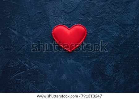 Red heart close up on dark blue background for Valentine's Day greeting card with copy space. 