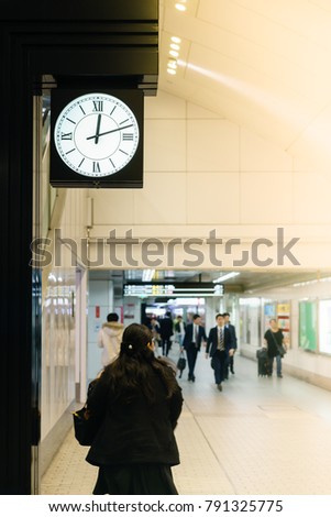 People walking at subway station for the train arriving with big clock time, background, Japan. 