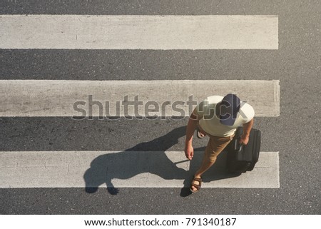 Tourist man walking with suitcase across the crosswalk at the junction street of city, Pedestrian safety, Top view