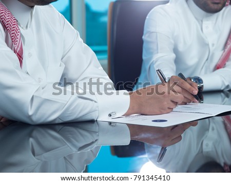 Saudi Businessmen Hands Signing a document, contract Royalty-Free Stock Photo #791345410