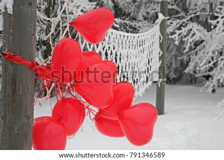 Red balloons with heart shape on the snow, winter background