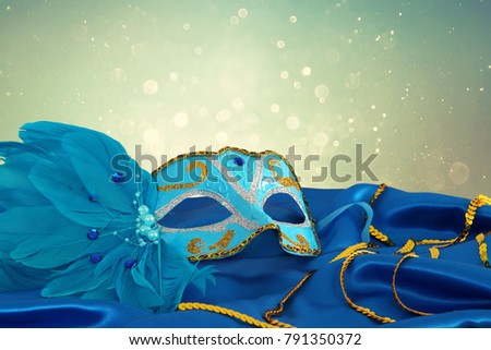 Image of elegant blue and gold venetian mask over blue silk fabric background