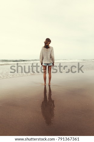 Young woman looking out to the sea on a cloudy day. 