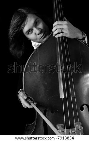 melancholy musician with a contrabass over black background. bnw