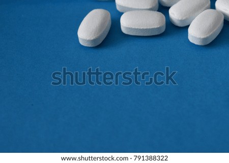 white pills on a blue background Royalty-Free Stock Photo #791388322