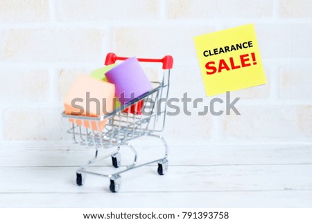 Selective focus of shopping cart or trolley with yellow sticky notes written with 'CLEARANCE SALE'. Shopping theme.