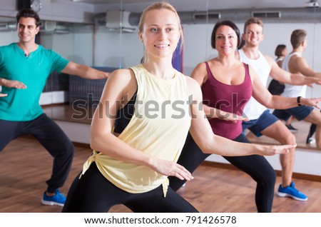 Ordinary people learning zumba steps in dance hall