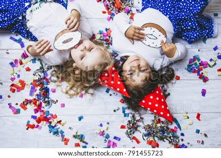 Two little girls child fashion colorful confetti on the floor and in festive hats cute and beautiful with a picture of donuts