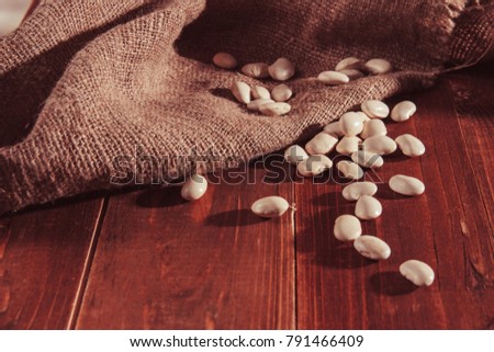 Navy bean or White bean on wooden background on burlap