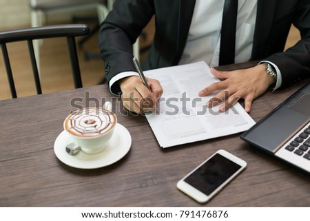 Close up businessman is signing a contract, business contract details at coffee shop