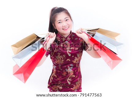 Young asian woman wearing chinese dress traditional cheongsam with Carrying a shopping bag and smile. Chinese New Year Festivities, New Year Celebration, Shopping concept, on white background.