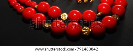 Red coral stone necklace beads decorated with golden beads isolated in dark background Royalty-Free Stock Photo #791480842