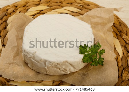 Camembert cheese with parsley over the wooden background