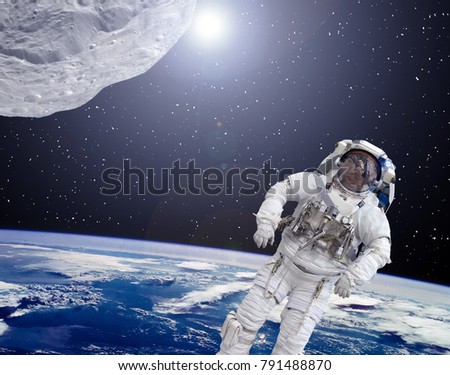 Asteroid aproaches to the earth.  Astronaut flies in space. Cosmic scene. The elements of this image furnished by NASA.
