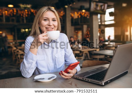 Business woman working on laptop and phone in a cafe