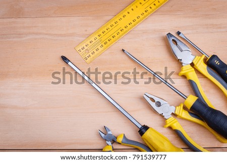 On a wooden background, a layout of pliers, screwdrivers and a ruler. Close-up. Top view.