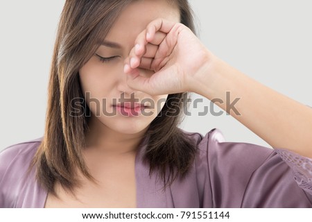 Asian women in purple robes have itching in the eye against gray background Royalty-Free Stock Photo #791551144
