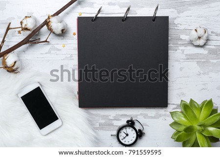 Black paper notebook, mobile phone, alarm clock,green plants and cotton flower. Flat lay mockup for inspiration quote.